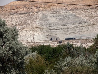 [Close-up of the tunnel openings through which a tractor trailer has just exited heading east. The hillside is naturally all rock and no vegetation.]